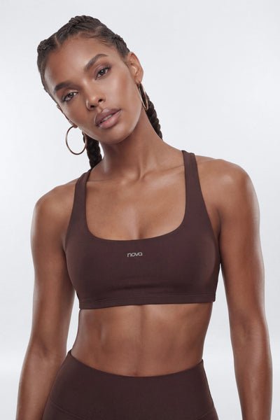 Woman wearing a brown sports bra with a visible brand logo on a white background