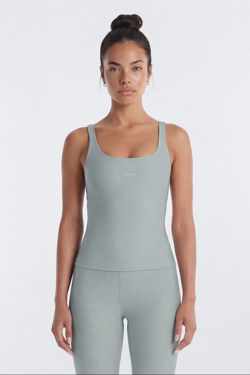 Woman wearing a light gray tank top and leggings on a white background