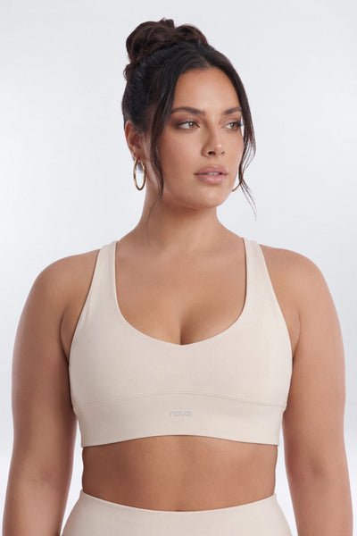Woman wearing a beige sports bra on a white background