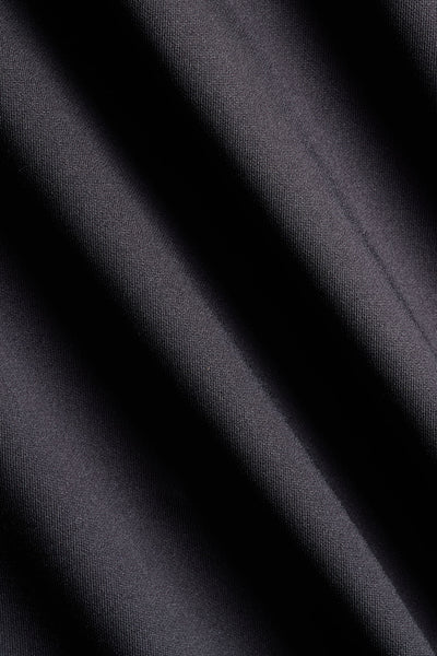 A close-up of dark charcoal gray fabric with soft diagonal folds and a fine woven texture.