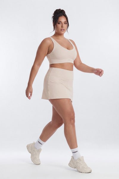 Woman wearing a beige athletic outfit on a white background
