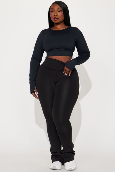 Person wearing a black long-sleeve crop top and black high-waisted pants on a white background
