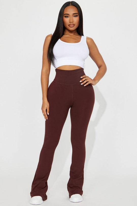 Woman wearing a white top and brown high-waisted pants on a white background