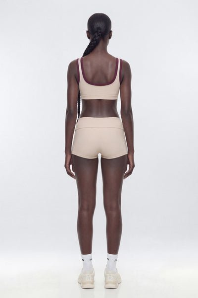 Person wearing a beige sports bra and shorts set on a white background