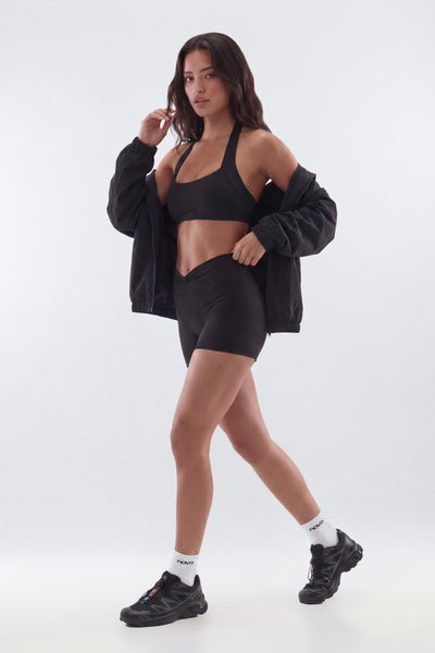 Woman in black athletic wear posing on a white background