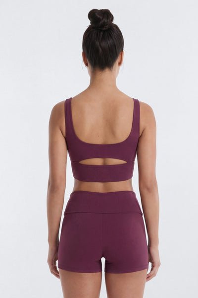 Person wearing a purple sports bra and shorts set on a white background