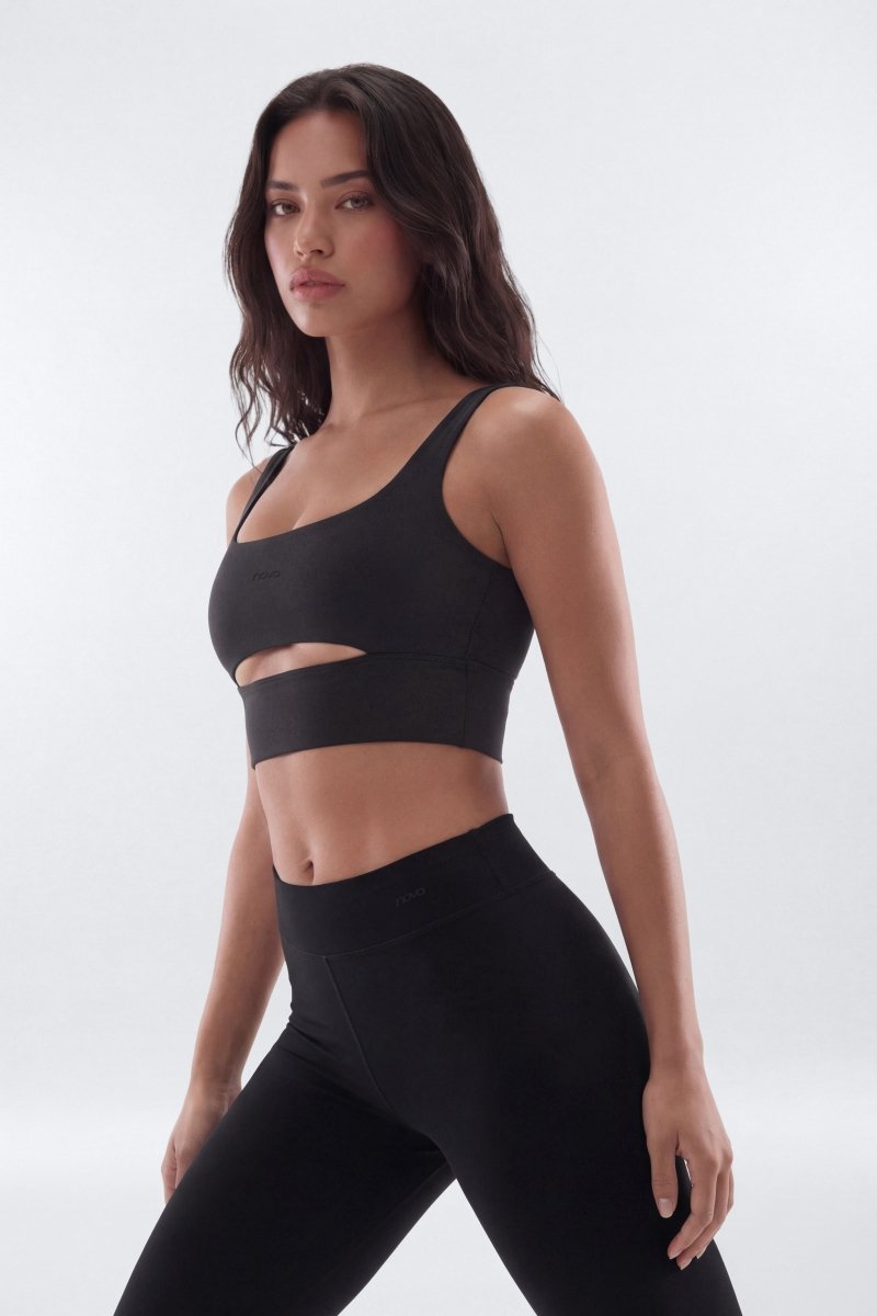 Woman wearing a black sports bra and leggings on a white background