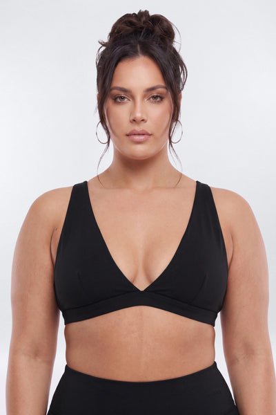 Woman wearing a black sports bra against a white background