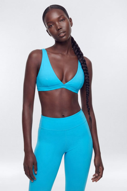 Woman wearing a blue sports bra and leggings on a white background