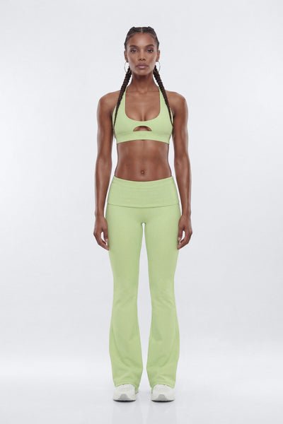 Woman wearing a green sports bra and leggings set on a white background