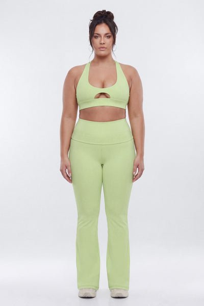Woman wearing a green sports bra and leggings set on a white background