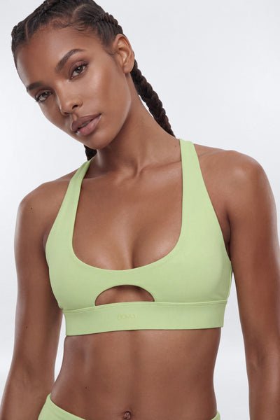 Woman wearing a light green sports bra against a white background
