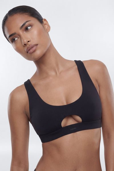 Woman wearing a black sports bra against a white background