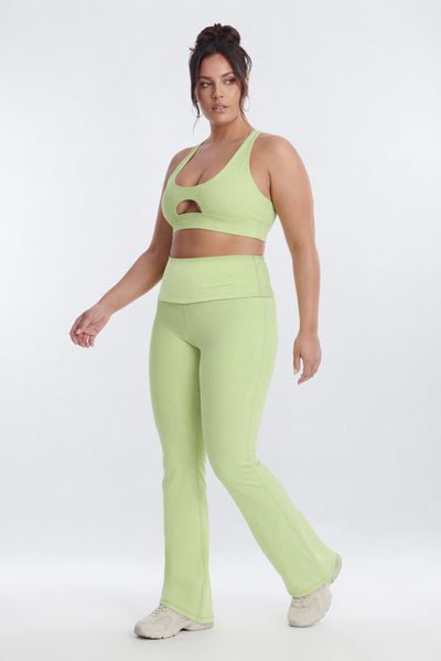 Woman wearing a light green sports bra and leggings set on a white background