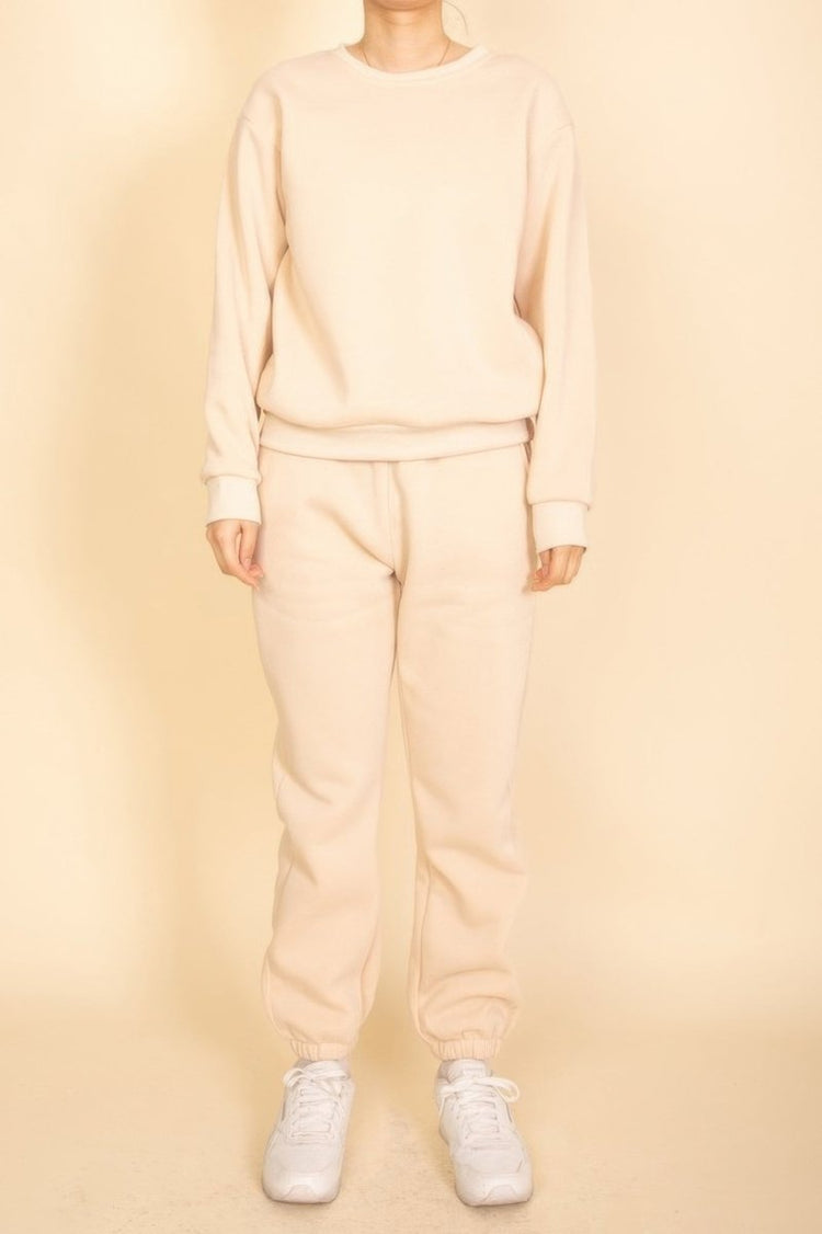 Person wearing a beige tracksuit against a beige background