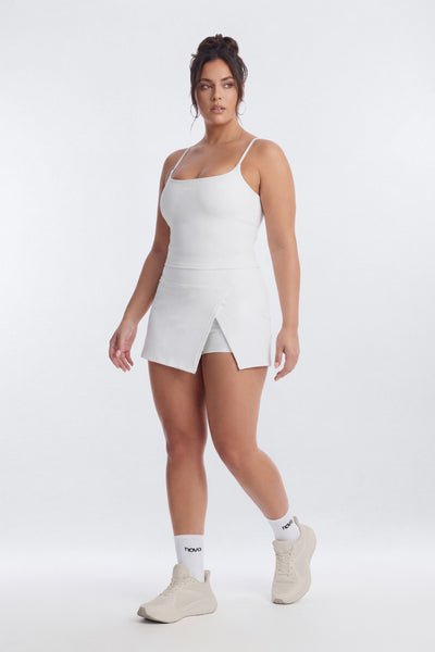 Woman wearing a white sleeveless top and shorts set on a white background