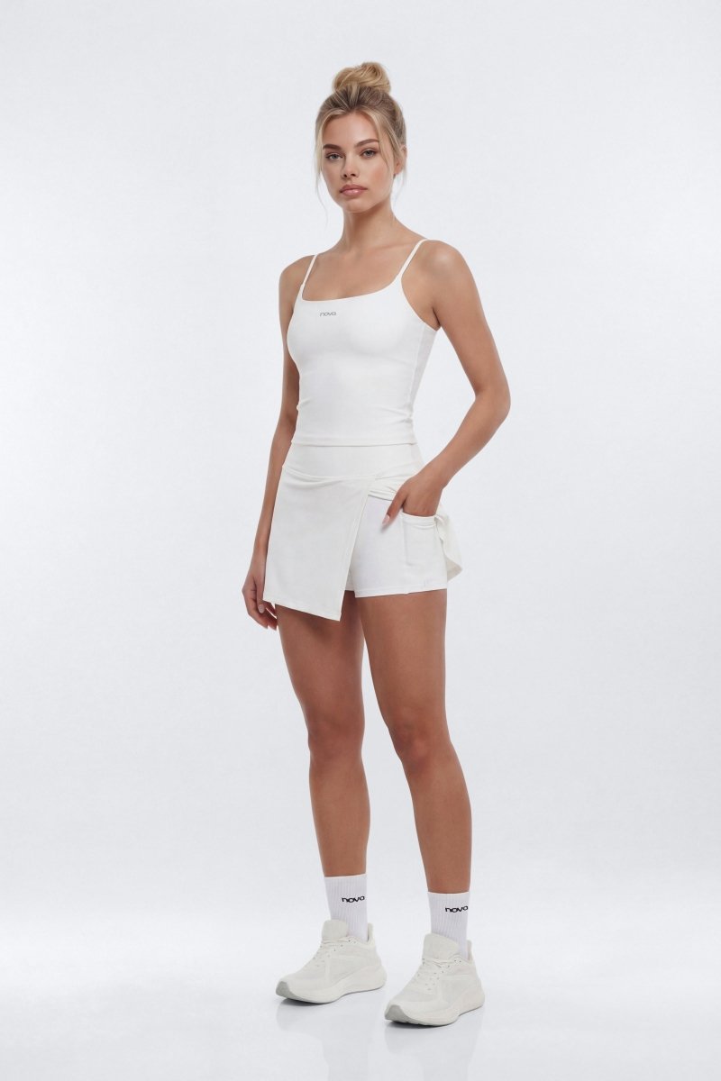 Woman wearing a white tank top and shorts on a white background