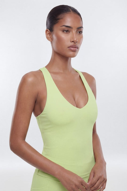 Woman wearing a light green tank top against a white background