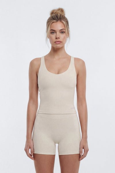 Woman wearing a beige tank top and shorts set on a white background