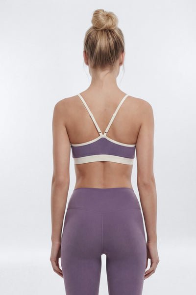 Woman wearing a purple sports bra and leggings on a white background