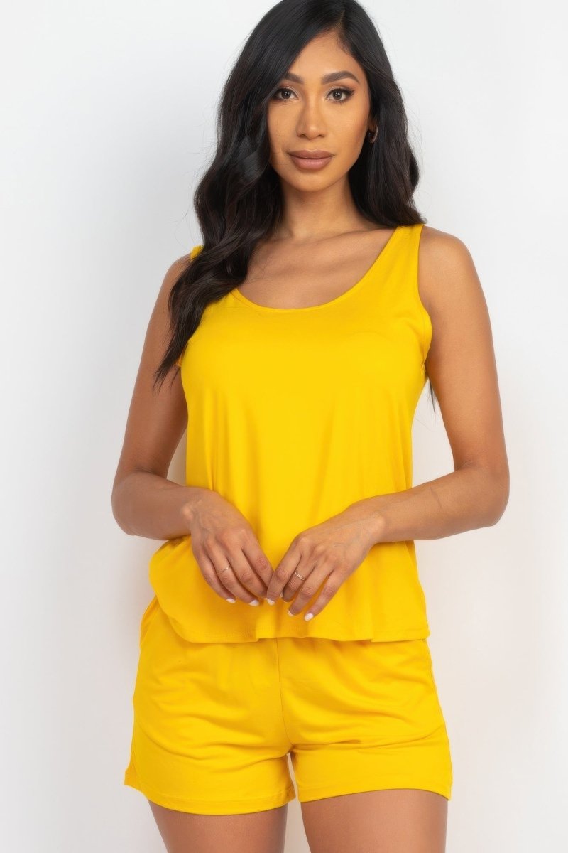 Woman wearing a yellow sleeveless top and shorts set on a white background