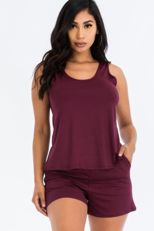 Woman wearing a maroon sleeveless top and shorts set on a white background