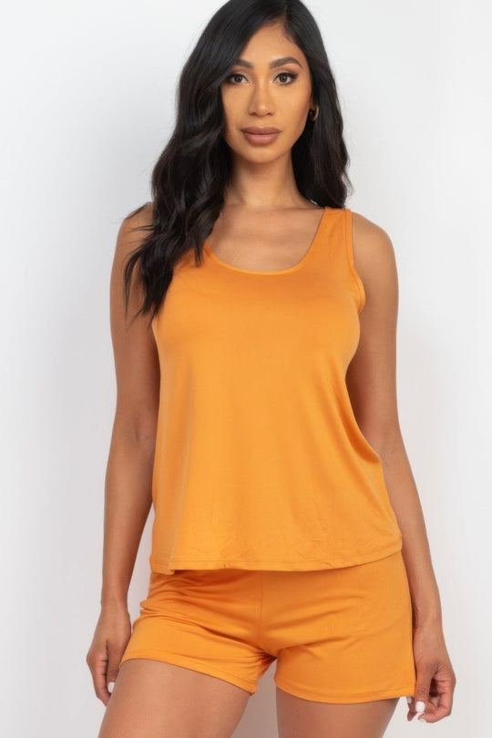 Woman wearing an orange tank top and shorts set on a white background