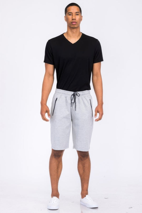 Man wearing a black t-shirt and gray shorts on a white background