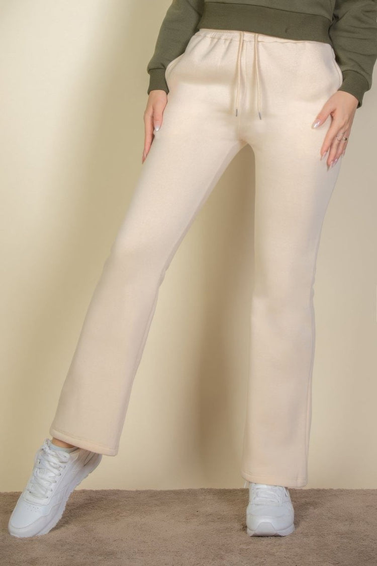Person wearing beige wide-leg pants and white sneakers on a plain background