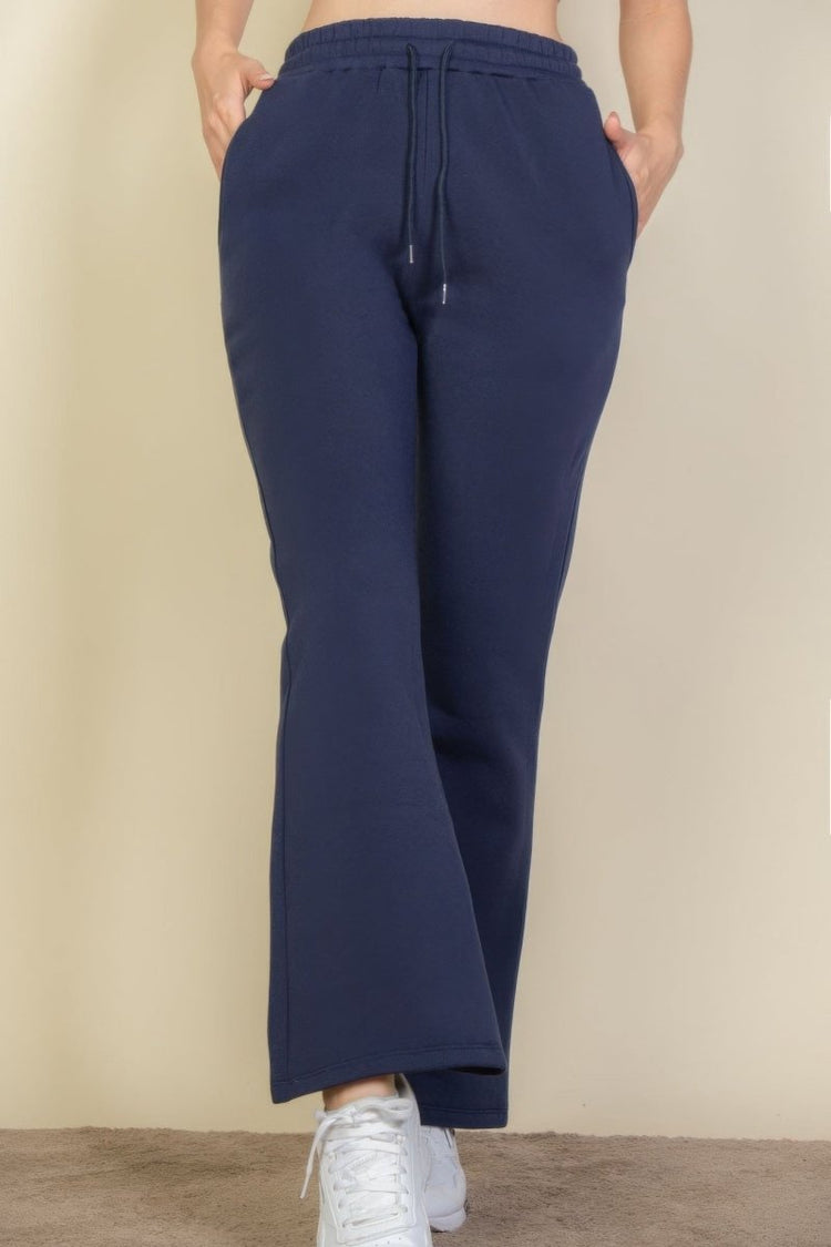 Navy blue sweatpants worn by a person on a beige background