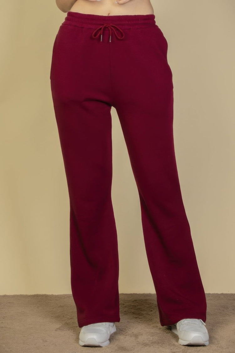 Maroon sweatpants worn by a person on a beige background