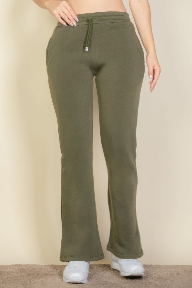 Green sweatpants worn by a person on a beige background