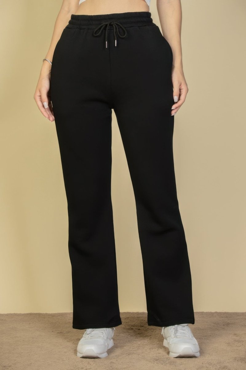 Black pants worn by a person on a beige background