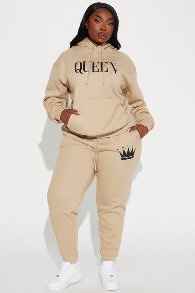 A woman modeling a beige matching hoodie and jogger sweatset. 