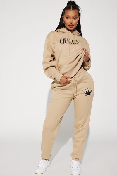 Person wearing a beige 'Queen' hoodie and jogger set on a white background