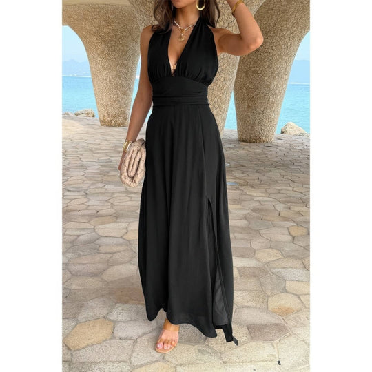 Woman in a black dress standing under stone arches with a scenic background