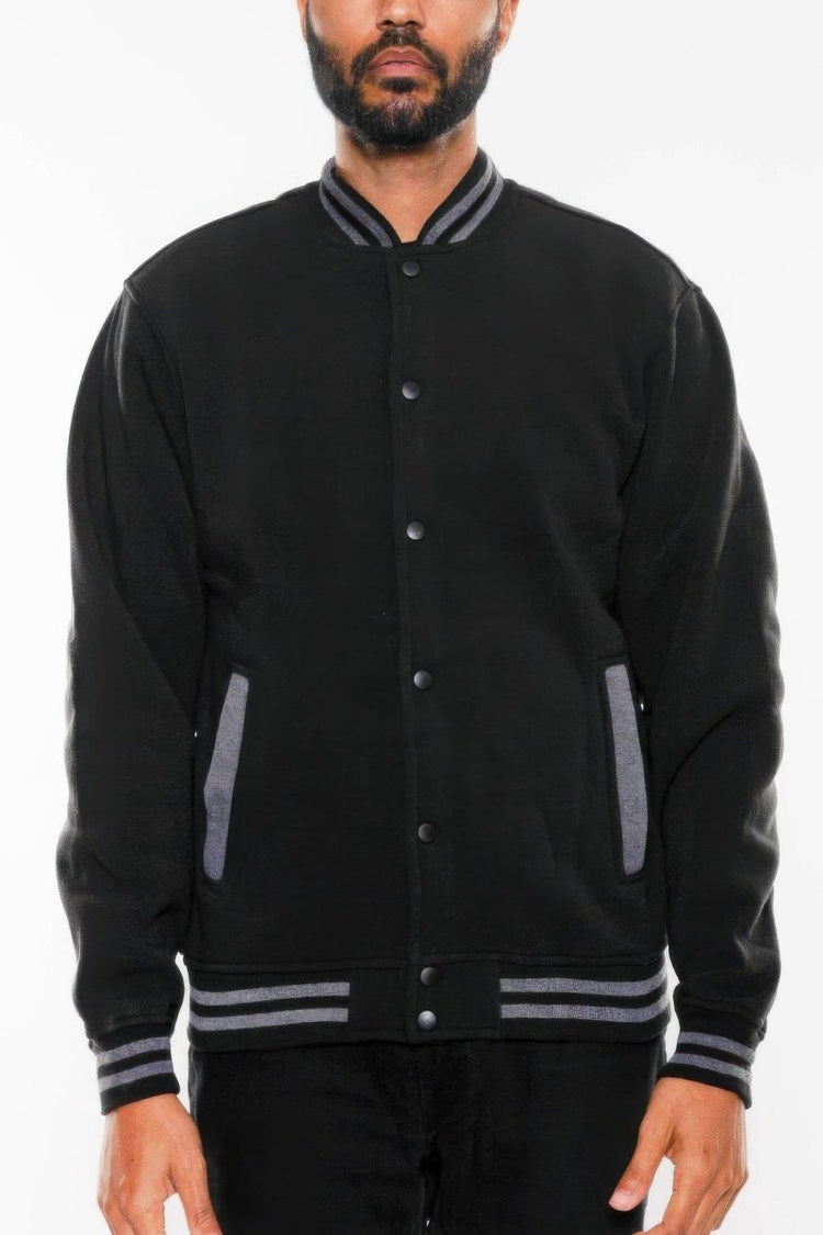 Black varsity jacket with gray accents worn by a person on a white background