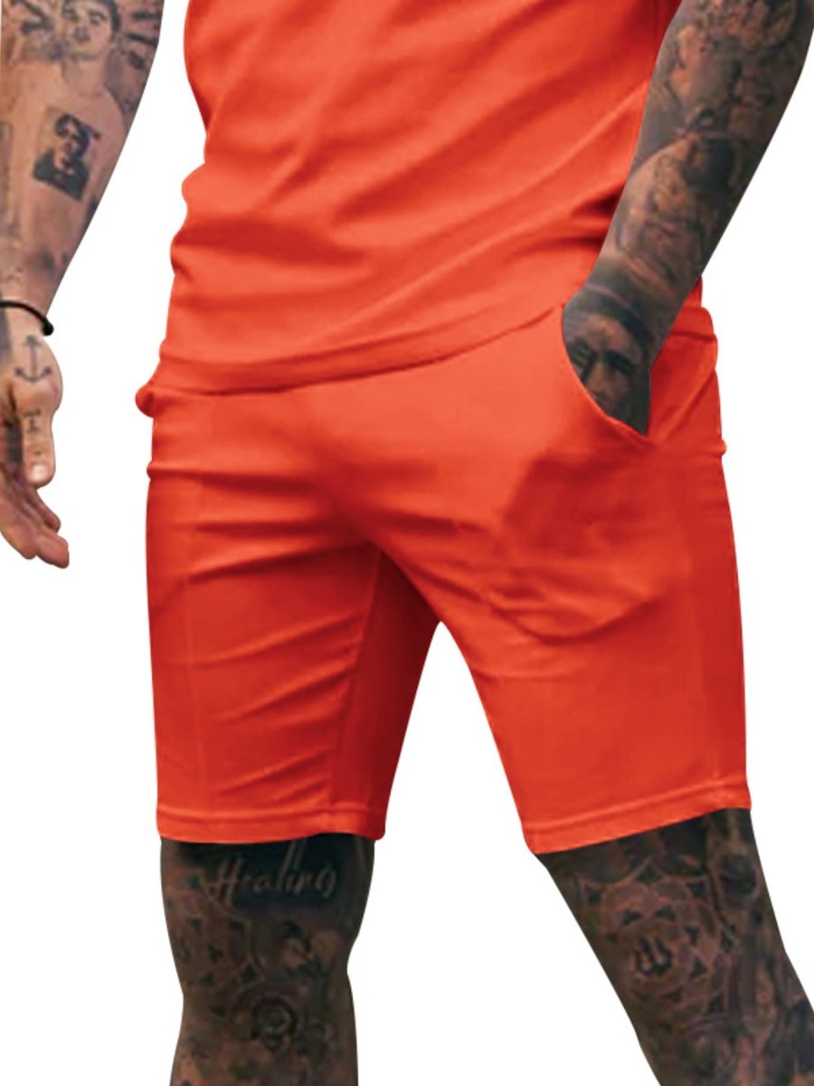 Orange shorts worn by a person with tattoos on a white background