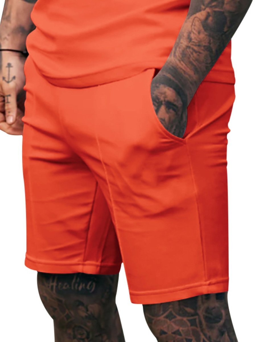 Orange shorts worn by a person with tattoos on a white background