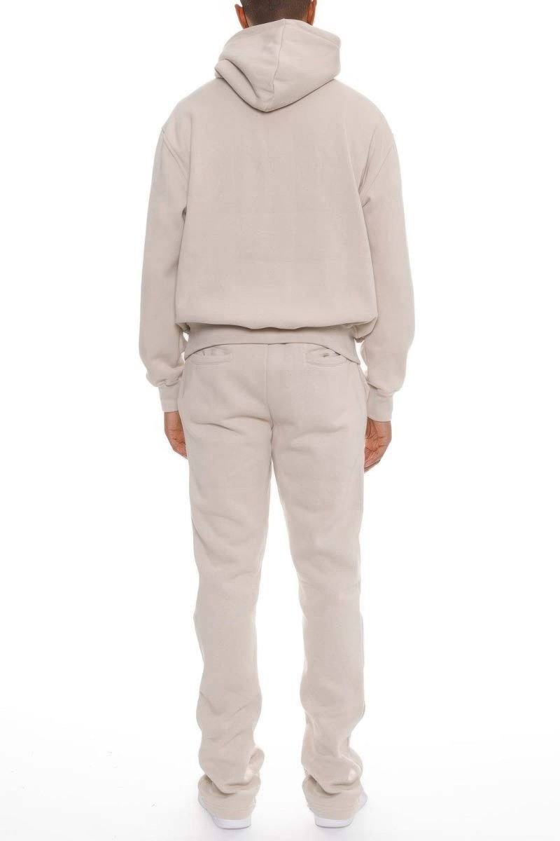 Person wearing a beige hoodie and pants set on a white background