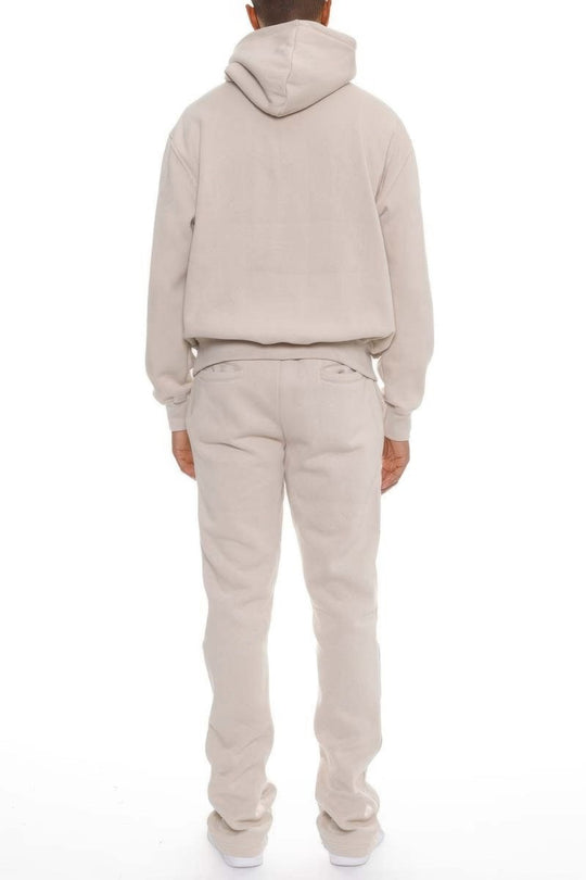 Person wearing a beige hoodie and pants set on a white background