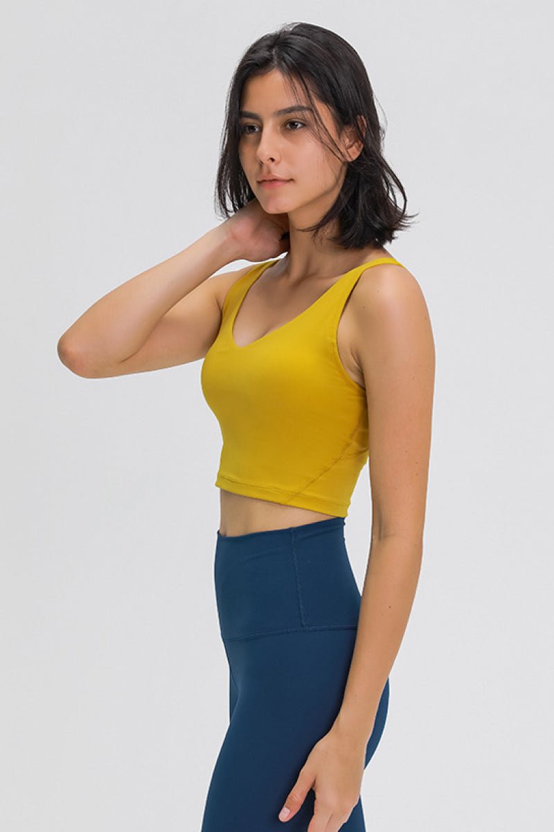 Woman wearing a yellow tank top and blue leggings on a white background