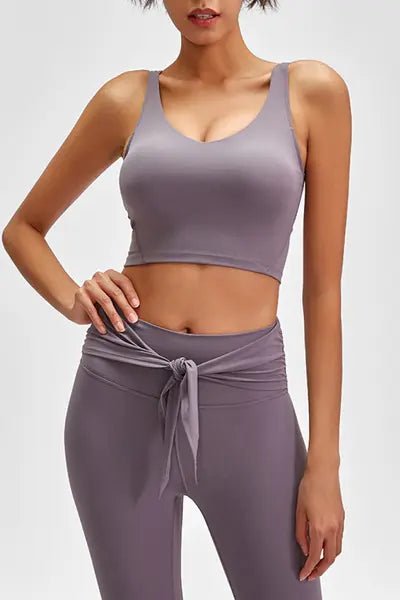 Woman wearing a matching lavender sports bra and leggings set on a white background
