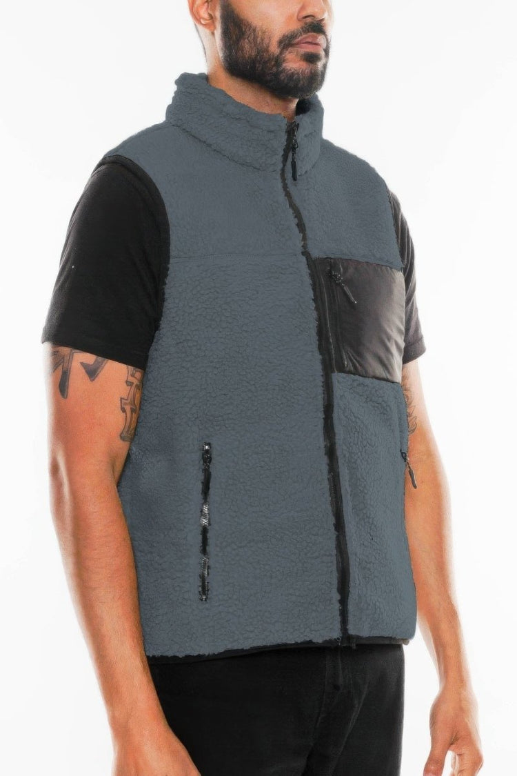 Man wearing a gray fleece vest with black accents on a white background