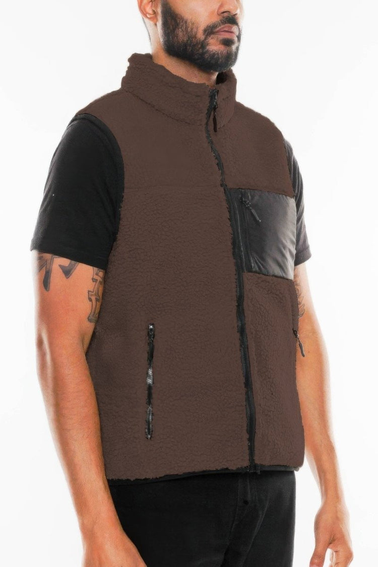 Man wearing a brown and black quilted vest on a white background