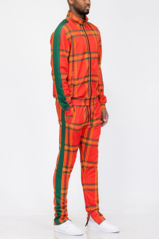 Person wearing a bright orange and green checkered tracksuit with white sneakers on a white background