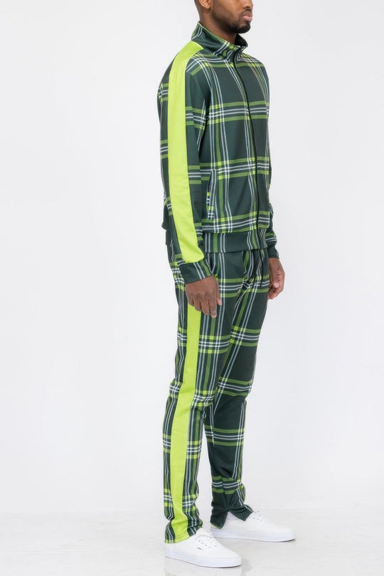 Person wearing a green plaid tracksuit with neon green stripes on a white background