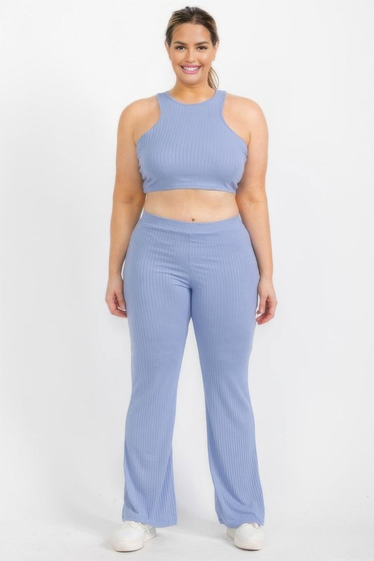 A woman modeling a matching ribbed two-piece activewear set in light periwinkle blue, featuring a sleeveless crop top and high-waisted flared pants, against a plain white studio background.