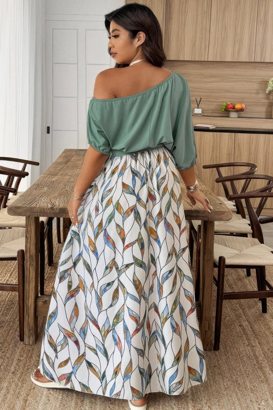 Woman in a green top and patterned skirt standing in a kitchen.