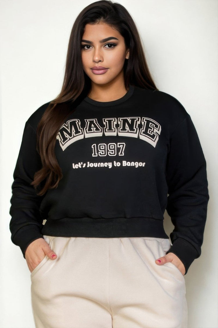 Woman wearing a black sweatshirt with 'MAINE 1997' text, standing against a white background